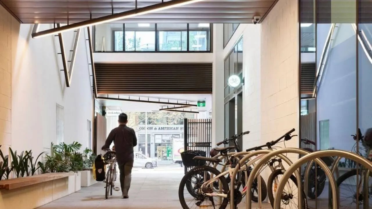 Man with bicycle plants bench bike rack exterior at Unilodge Melbourne City in Melbourne Student Accommodation