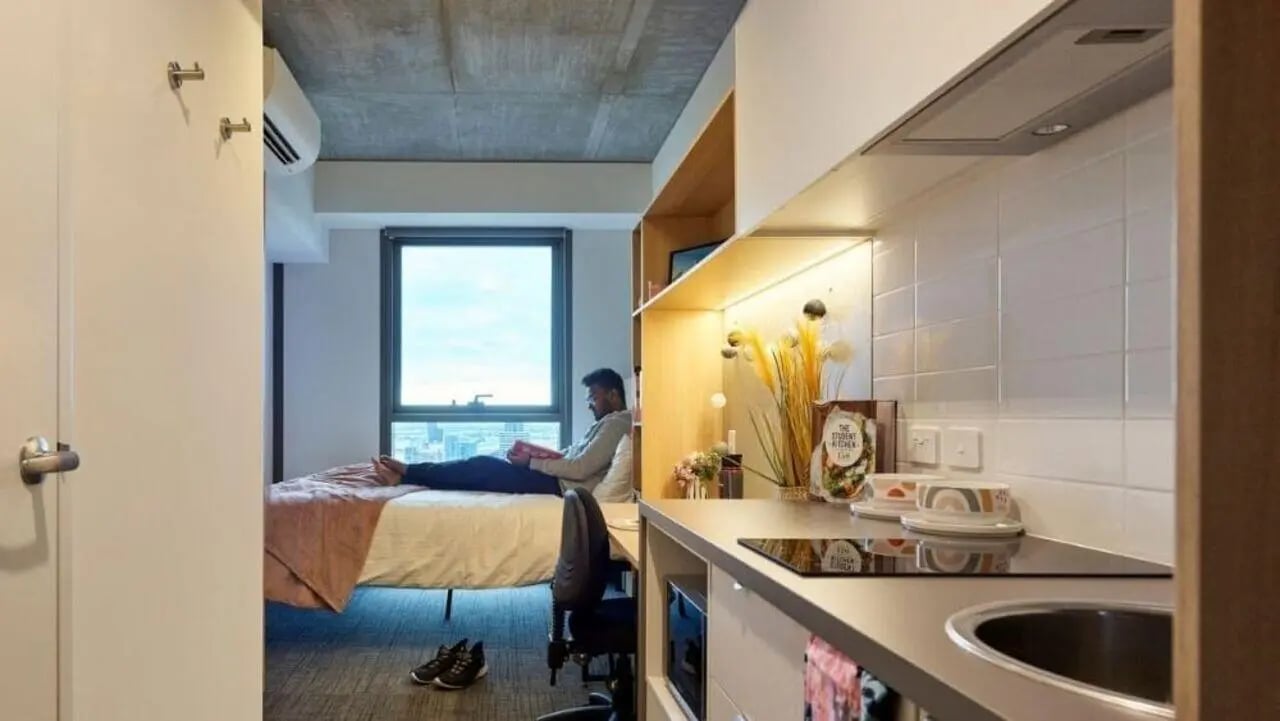 Bed desk kitchen counter sink and person bedroom kitchen at Unilodge Melbourne City in Melbourne Student Accommodation