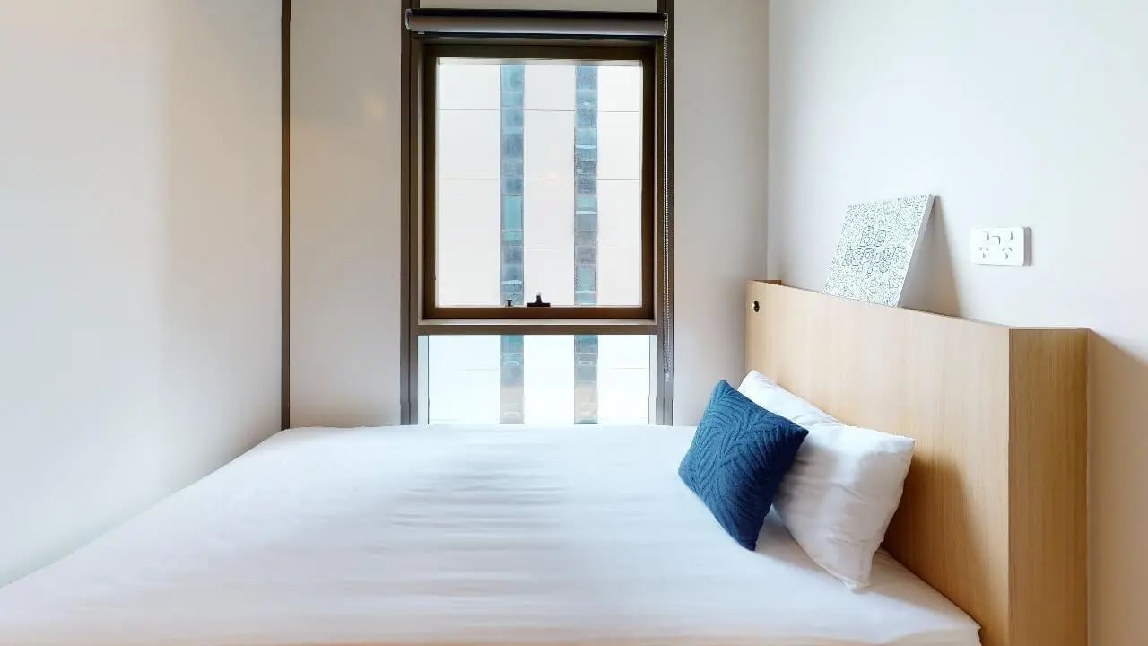 Bed with pillows artwork and window Bedroom at Unilodge Melbourne City in Melbourne Student Accommodation