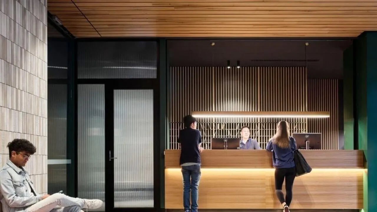 Reception desk people computers and wood paneling lobby at Unilodge Melbourne City in Melbourne Student Accommodation
