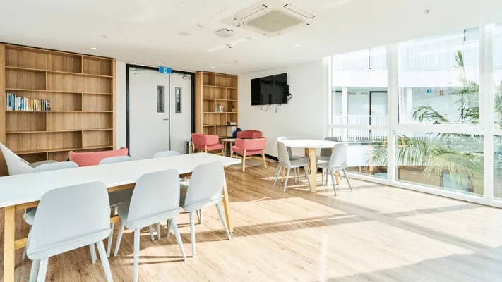 Tables chairs bookshelves and a television communal area at UniLodge Park Avenue in Melbourne Student Accommodation