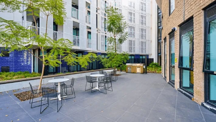 Outdoor courtyard with tables chairs and greenery exterior at UniLodge Park Avenue in Melbourne Student Accommodation