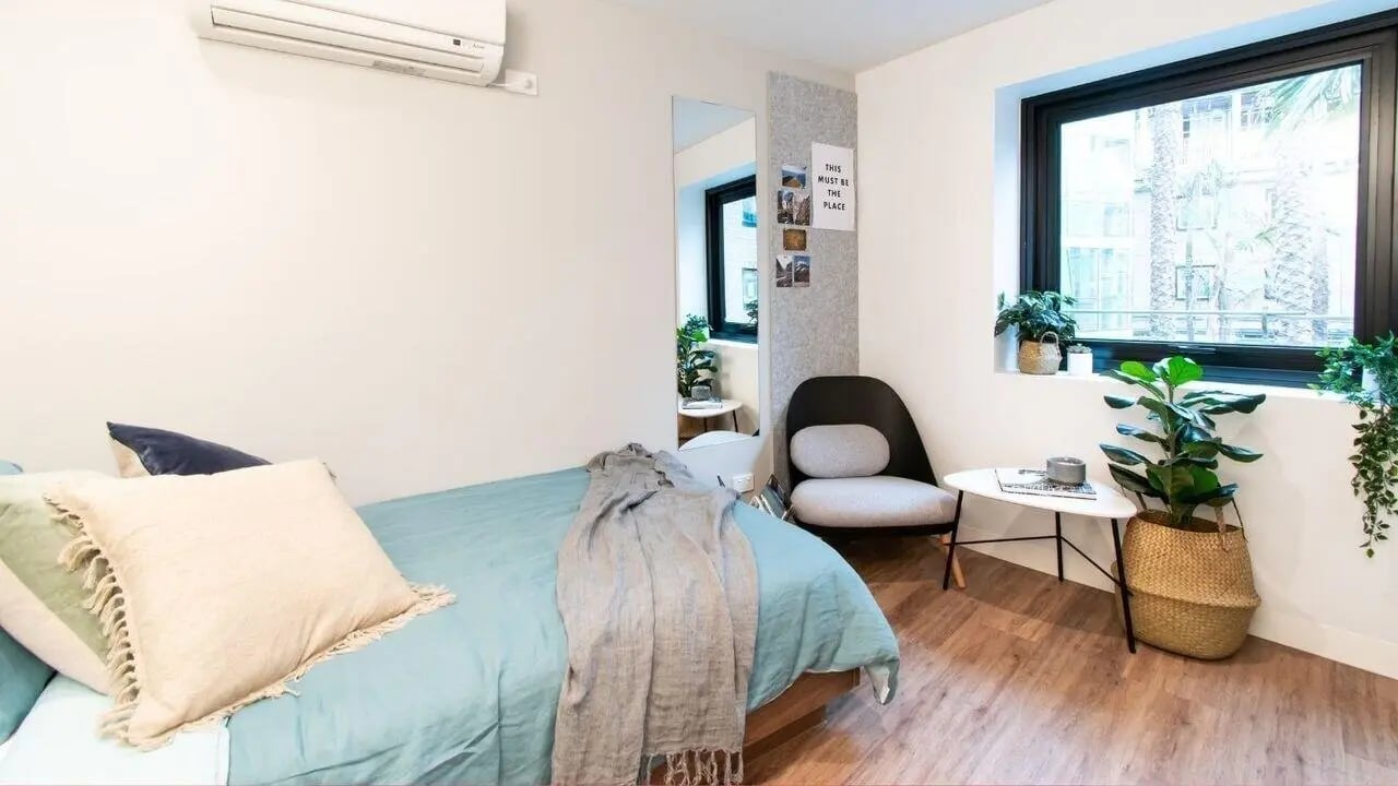 Bed with pillows throw chair and plants bedroom at UniLodge Park Avenue in Melbourne Student Accommodation