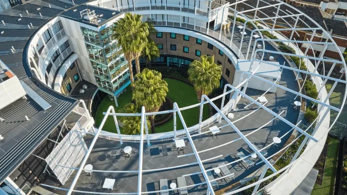 Courtyard with palm trees tables chairs exterior at UniLodge Park Avenue in Melbourne Student Accommodation