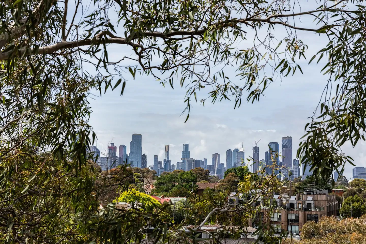 Apartment buildings framed by trees with city skyline exterior at UKO Royal Park in Melbourne Student Accommodation
