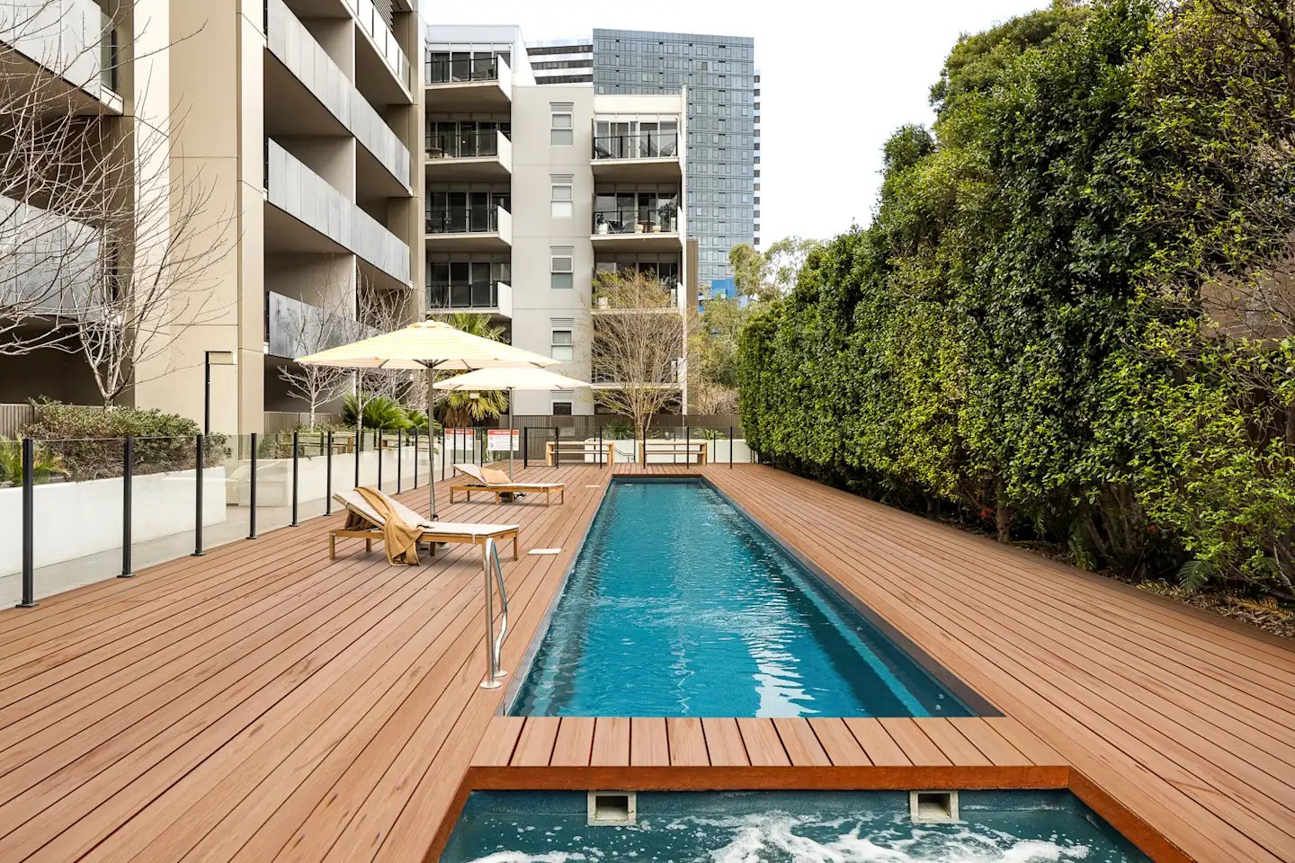 Pool with lounge chairs and umbrellas exterior at UKO Royal Park in Melbourne Student Accommodation