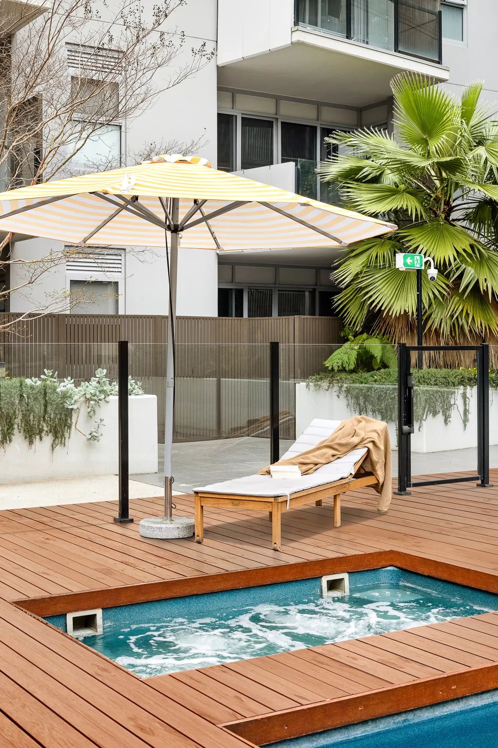 Jacuzzi with lounge chair under umbrella outdoor area at UKO Royal Park in Melbourne Student Accommodation