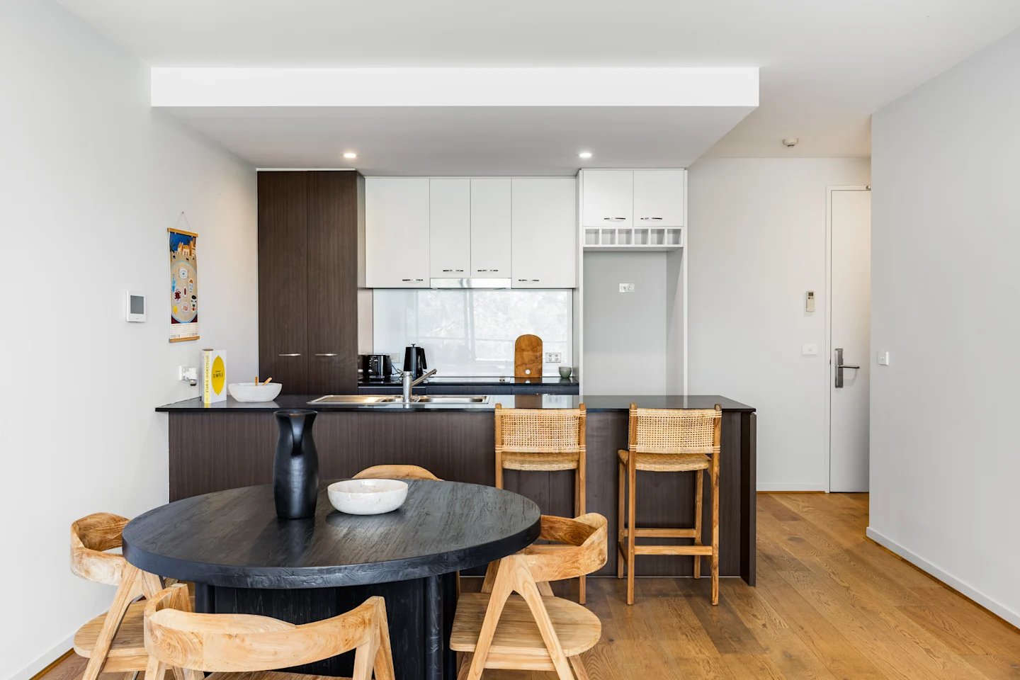 Dark dining table rattan stools modern kitchen living room at UKO Royal Park in Melbourne Student Accommodation