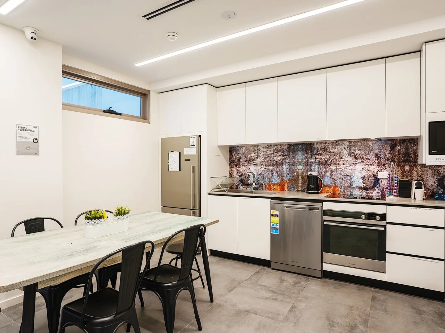 Table chairs refrigerator dishwasher oven kitchen at UKO Surry Hills in Sydney Student Accommodation