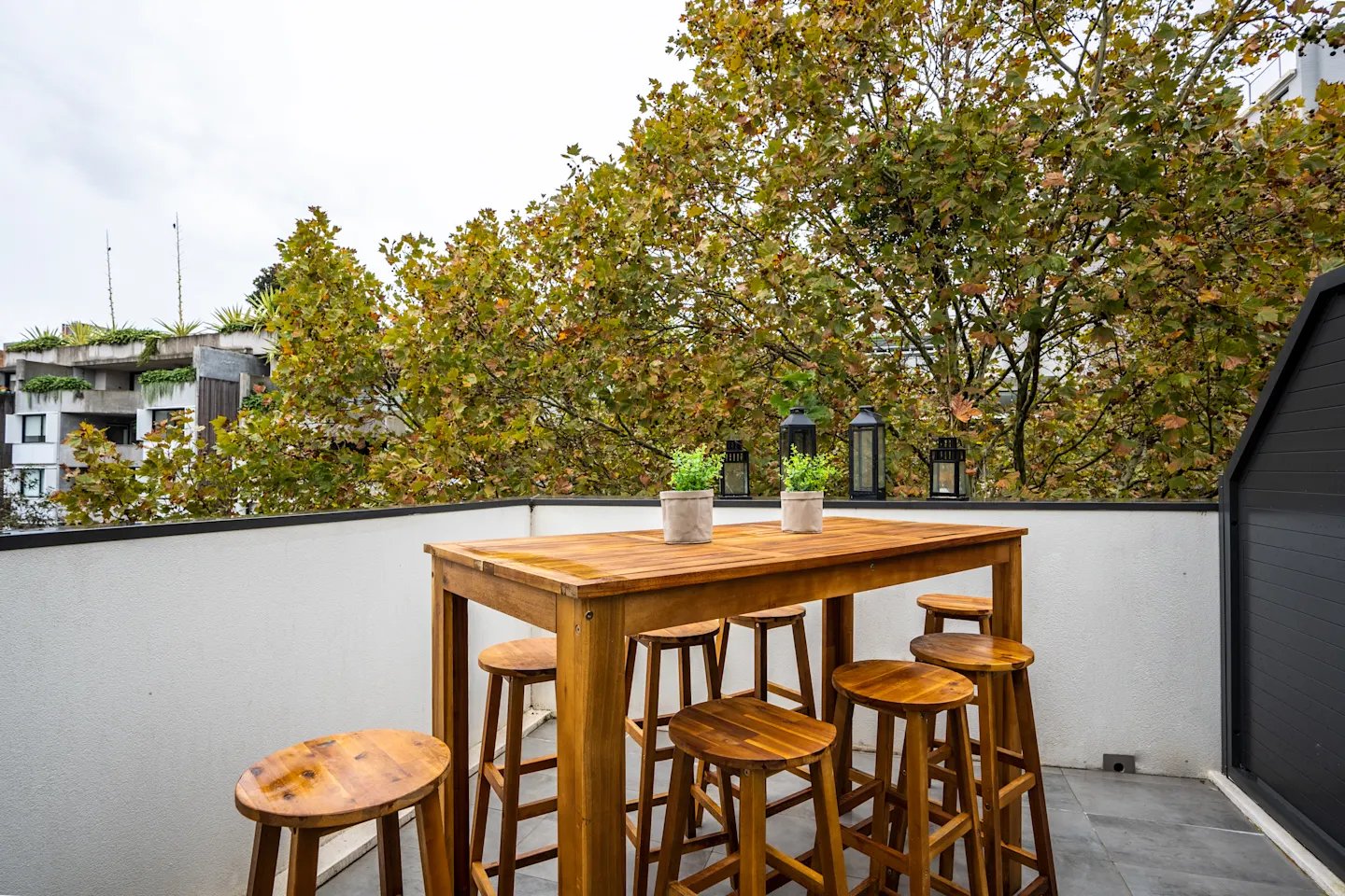 Wooden table with stools and plants balcony living area at UKO Surry Hills in Sydney Student Accommodation