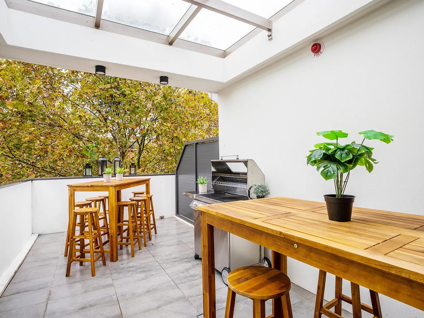 Wooden bar tables stools grill plant balcony exterior at UKO Surry Hills in Sydney Student Accommodation