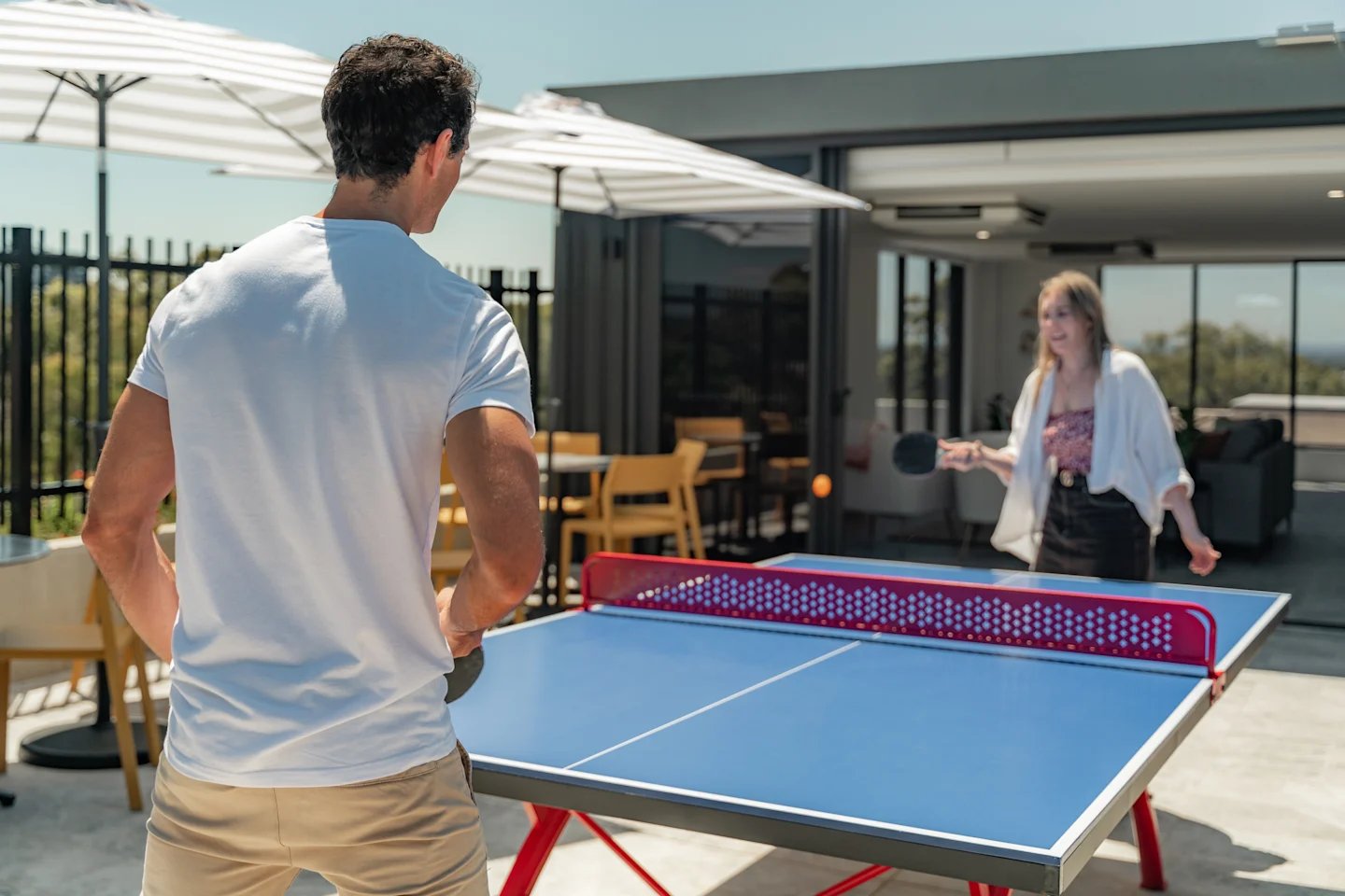 Students playing ping pong on an outdoor patio playing area at UKO Sutherland in Sydney Student Accommodation
