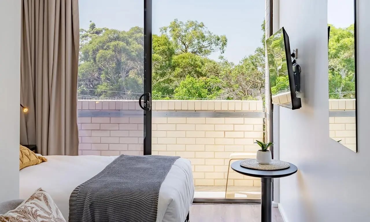 Bed curtains TV and plant bedroom at UKO Sutherland in Sydney Student Accommodation