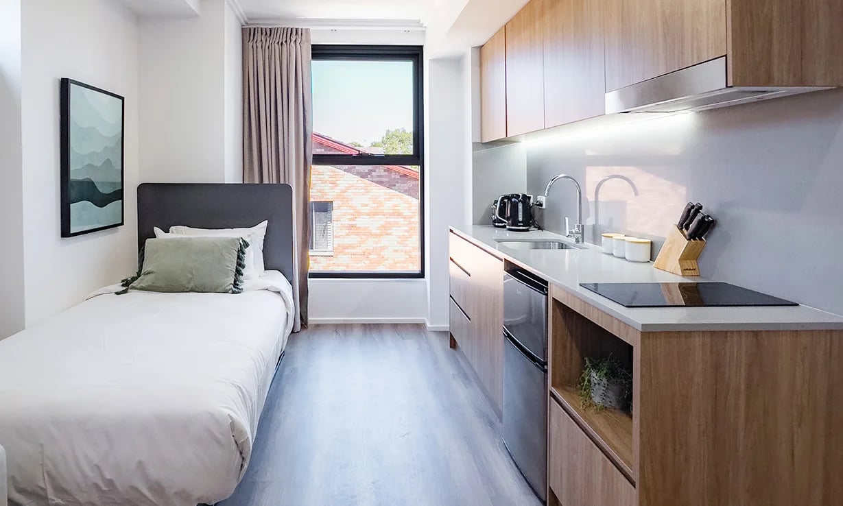 Single bed framed art modern kitchen area studio apartment at UKO Sutherland in Sydney Student Accommodation