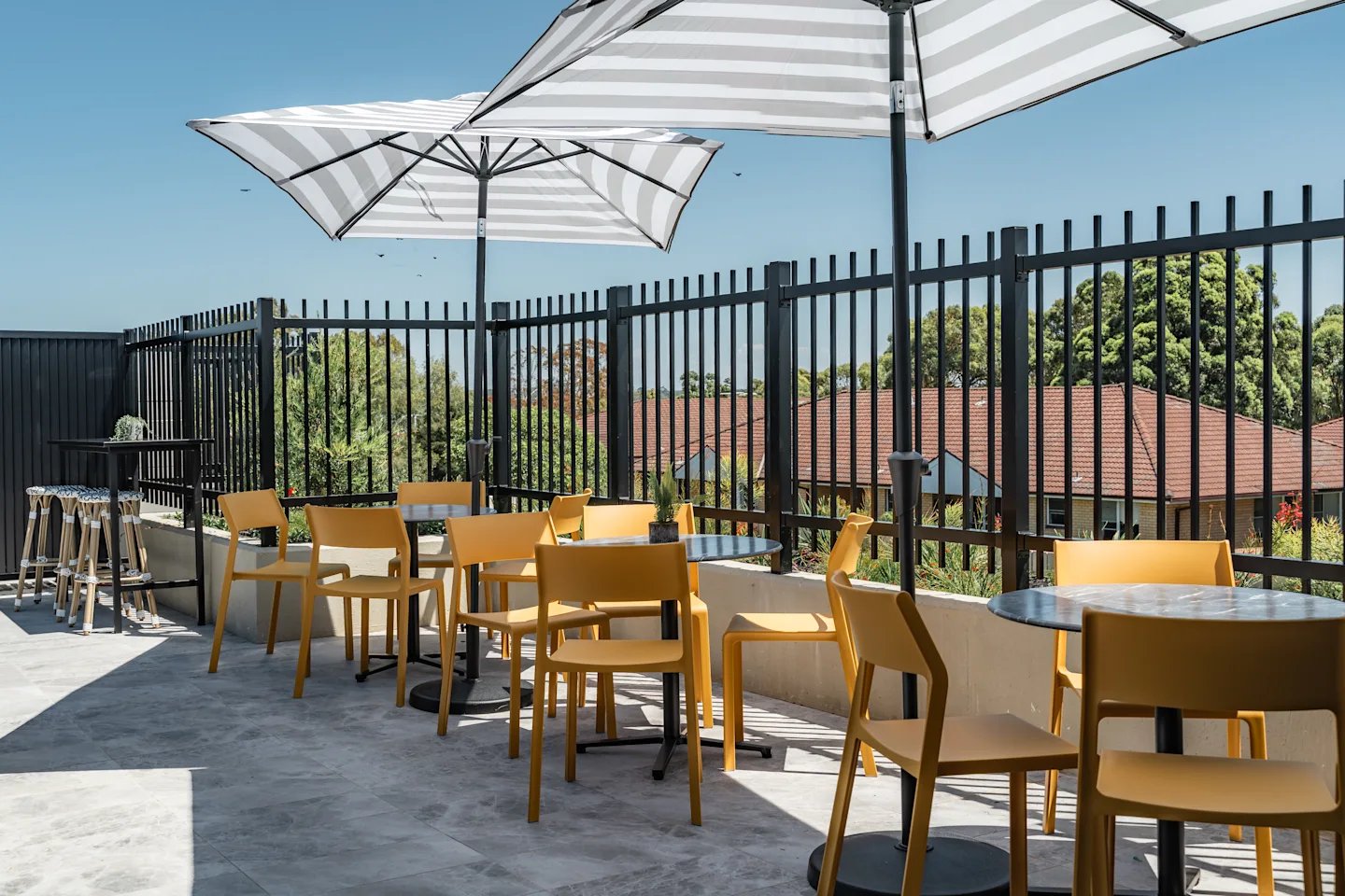 Outdoor seating area with yellow chairs and umbrellas patio area at UKO Sutherland in Sydney Student Accommodation