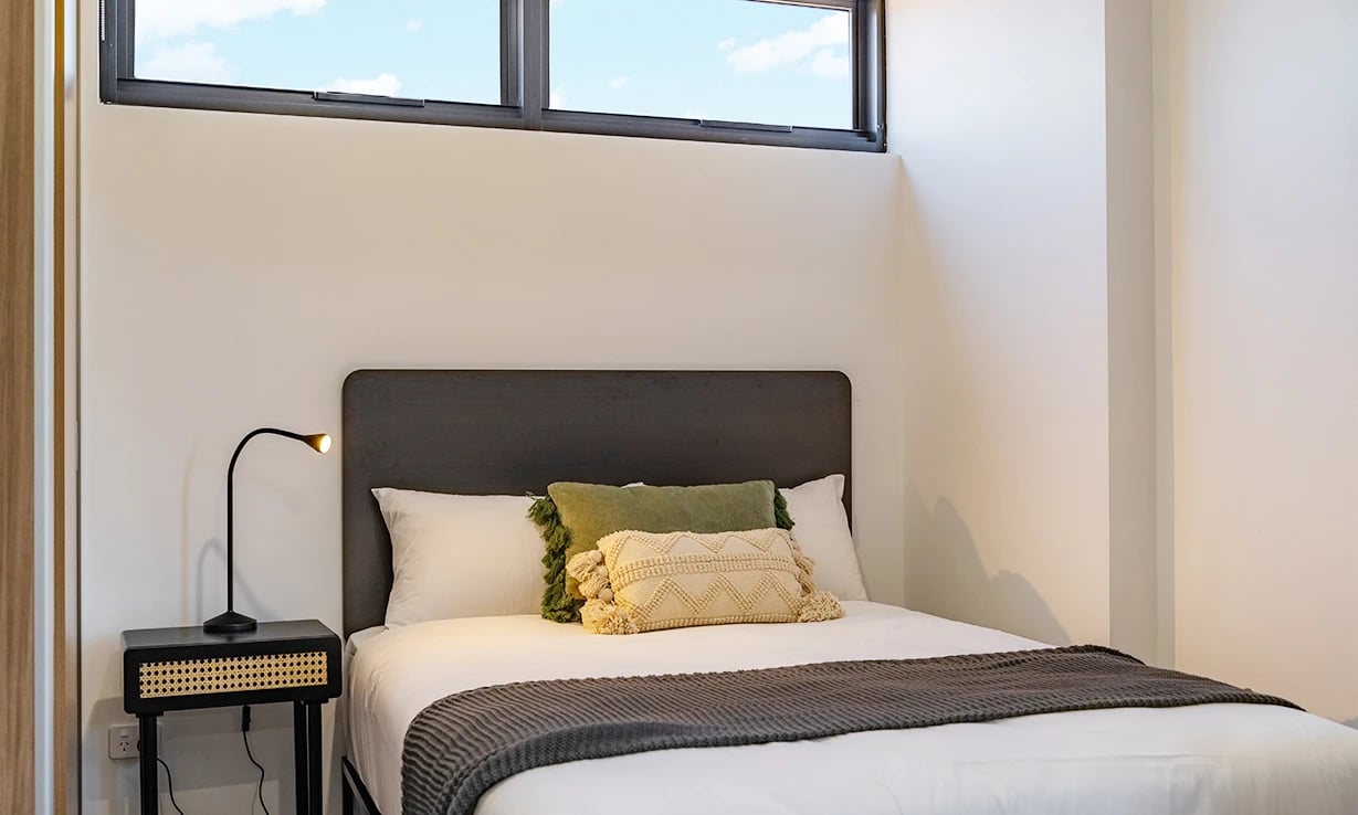 Bed with pillows and bedside lamp bedroom at UKO Sutherland in Sydney Student Accommodation