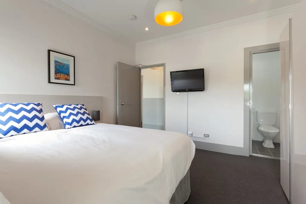 Bed with blue chevron pillows and ensuite bathroom Bedroom at ume Darlinghurst in Sydney Student Accommodation