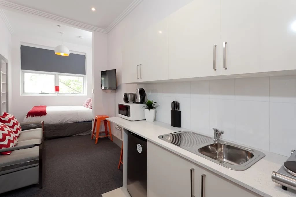 Bed couch kitchen sink and microwave studio apartment at ume Darlinghurst in Sydney Student Accommodation