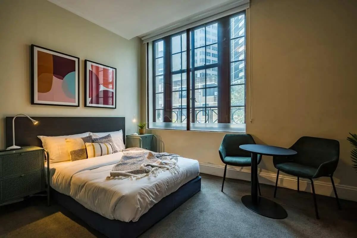 Bed nightstand paintings table chairs bedroom at ume Haymarket in Sydney Student Accommodation