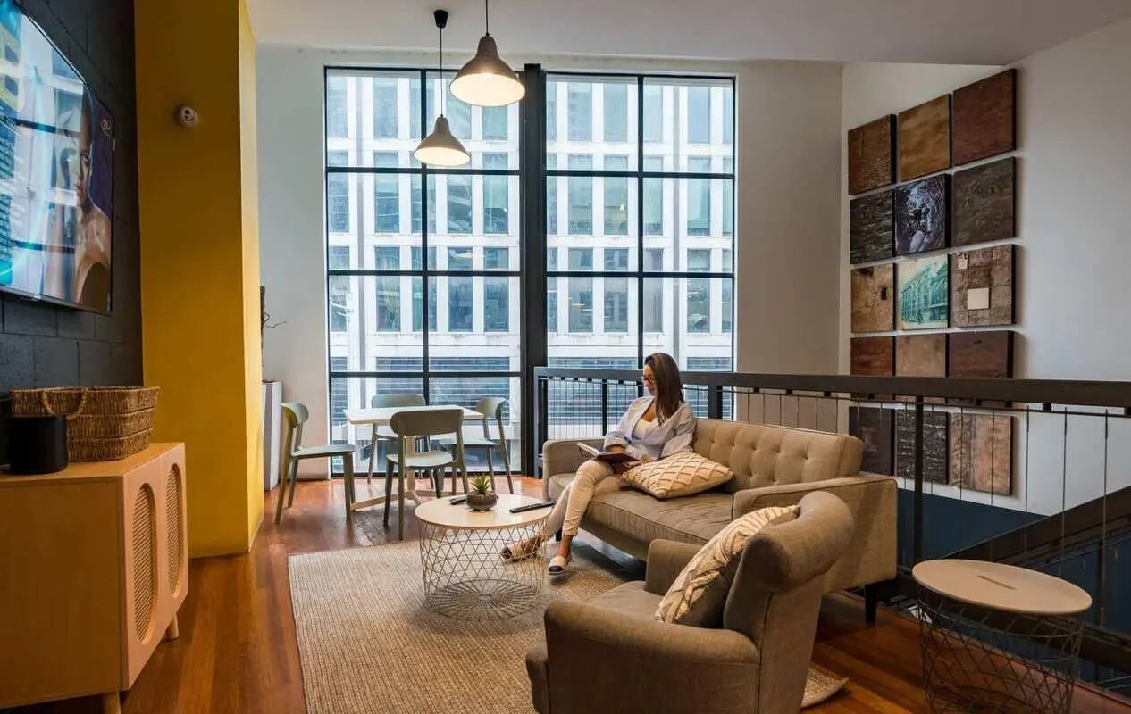 Woman reading on couch by large window living room at ume Haymarket in Sydney Student Accommodation