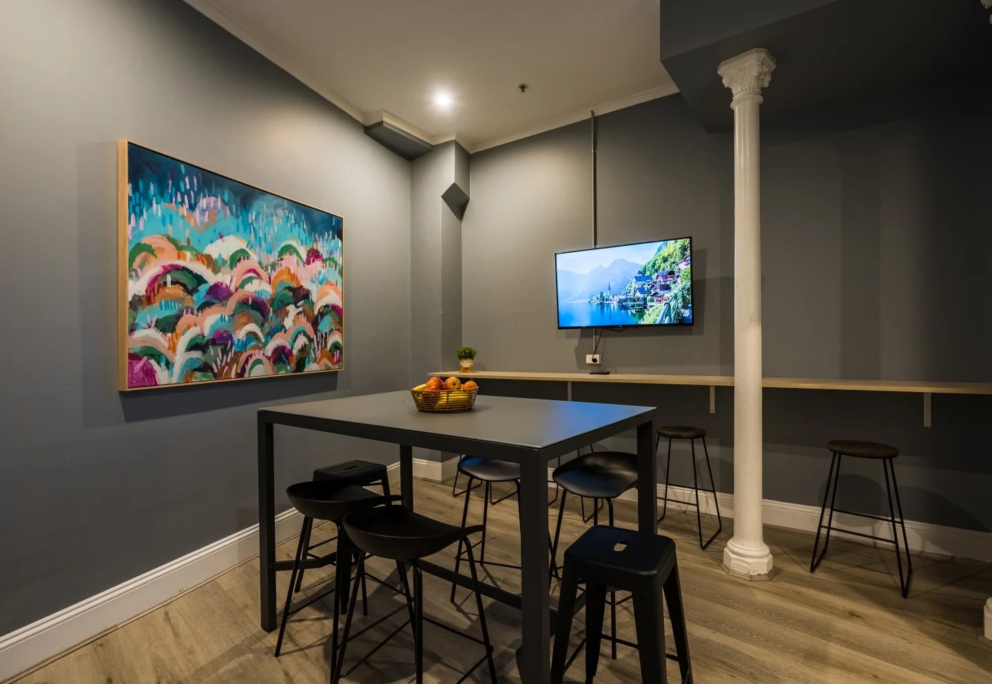 Table with stools artwork and television communal area at ume Haymarket in Sydney Student Accommodation