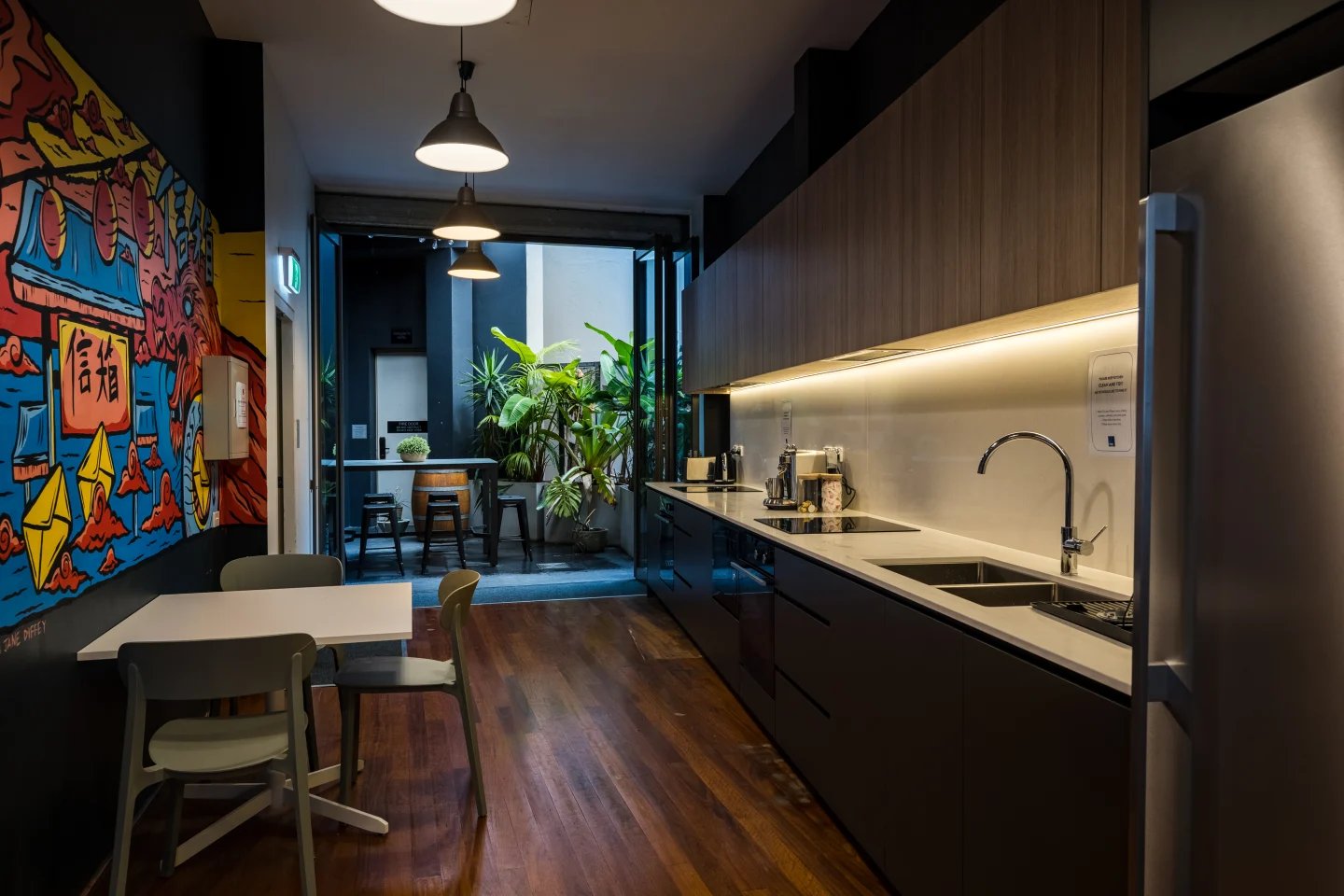 Modern kitchen with colourful mural and plants kitchen at ume Haymarket in Sydney Student Accommodation