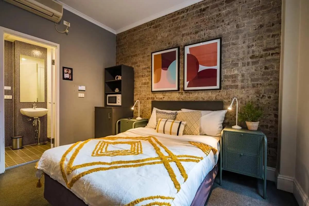 Bed with bedside tables art and bathroom Bedroom at ume Haymarket in Sydney Student Accommodation