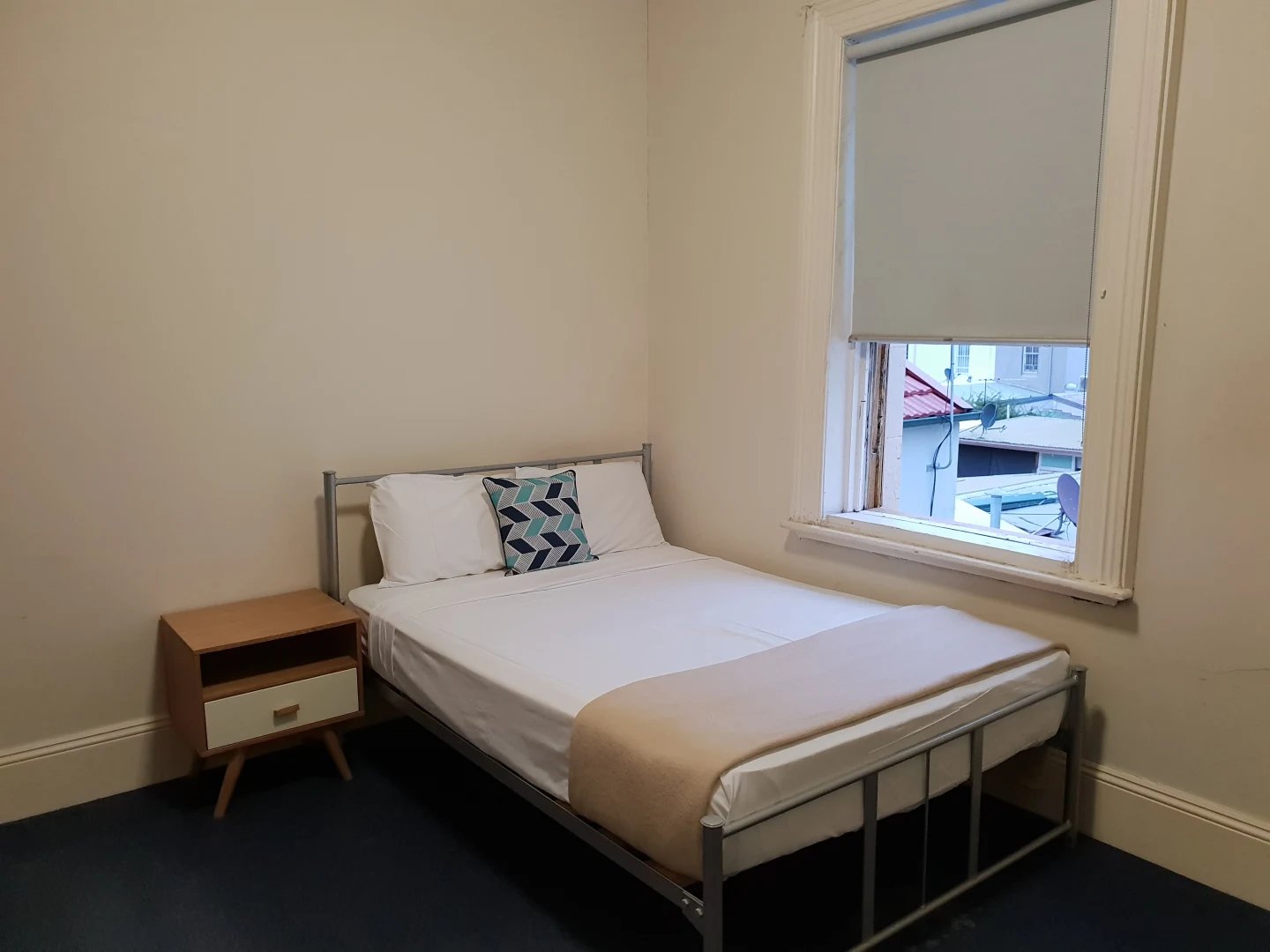 Bed with patterned pillow and bedside table bedroom at ume Redfern in Sydney Student Accommodation