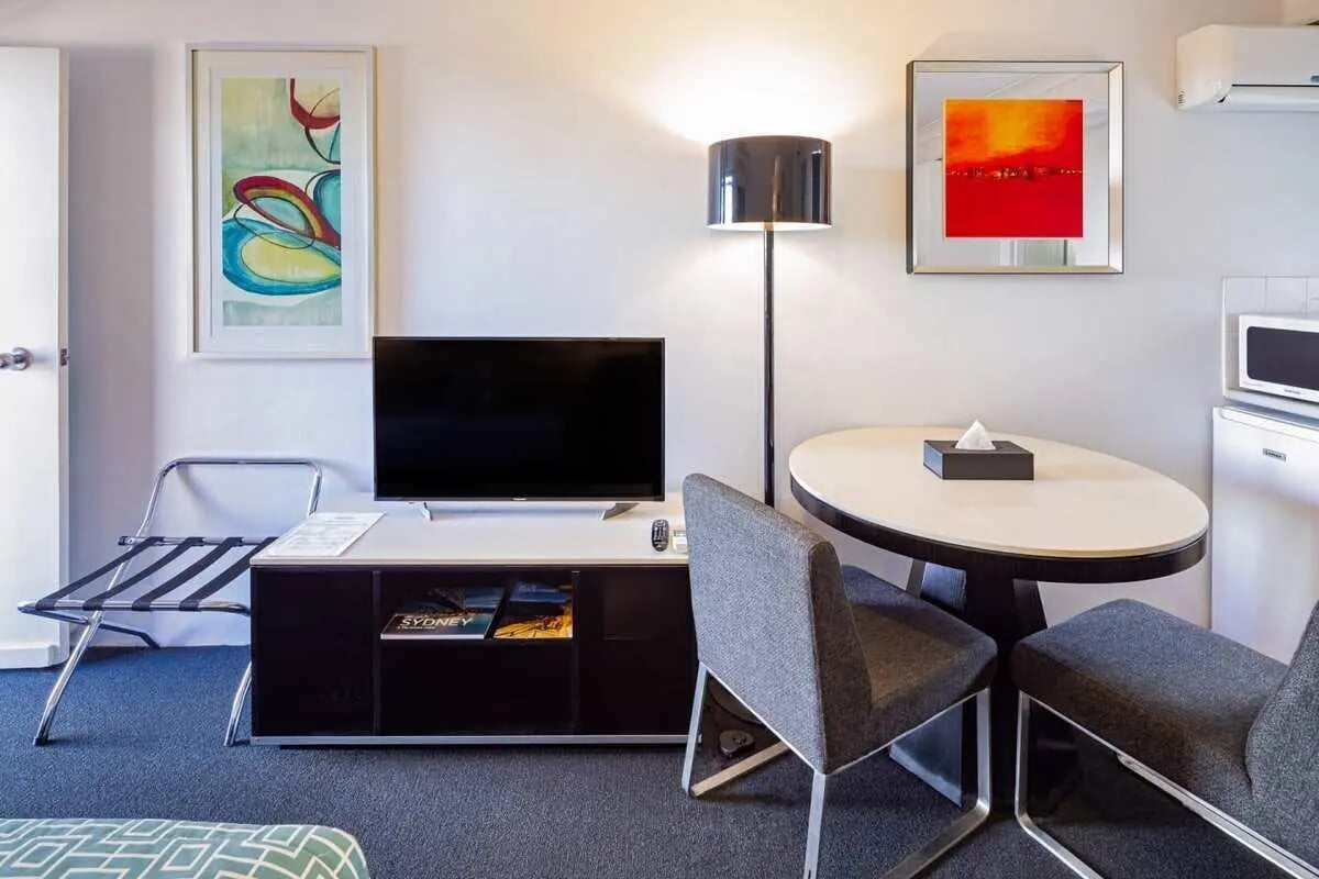 Flat screen TV luggage rack dining table with chairs Living room at ume Redfern Village in Sydney Student Accommodation