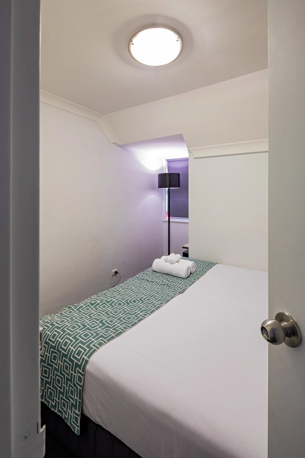 Bed with folded towels and lamp bedroom at ume Redfern Village in Sydney Student Accommodation