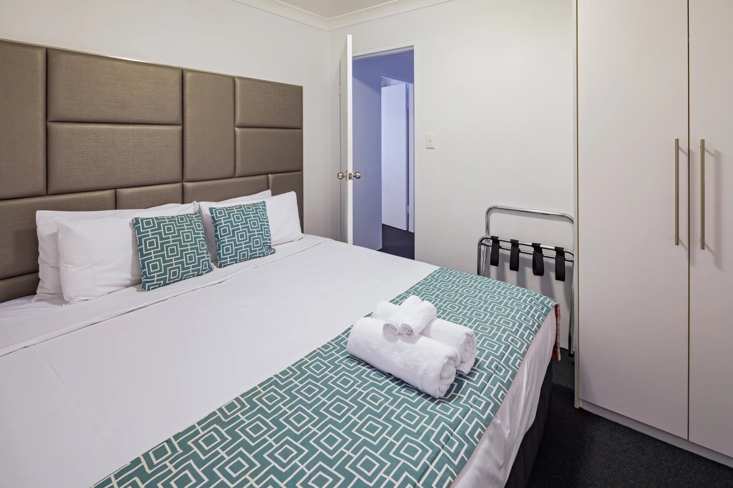 Bed with pillows luggage rack wardrobe bedroom at ume Redfern Village in Sydney Student Accommodation