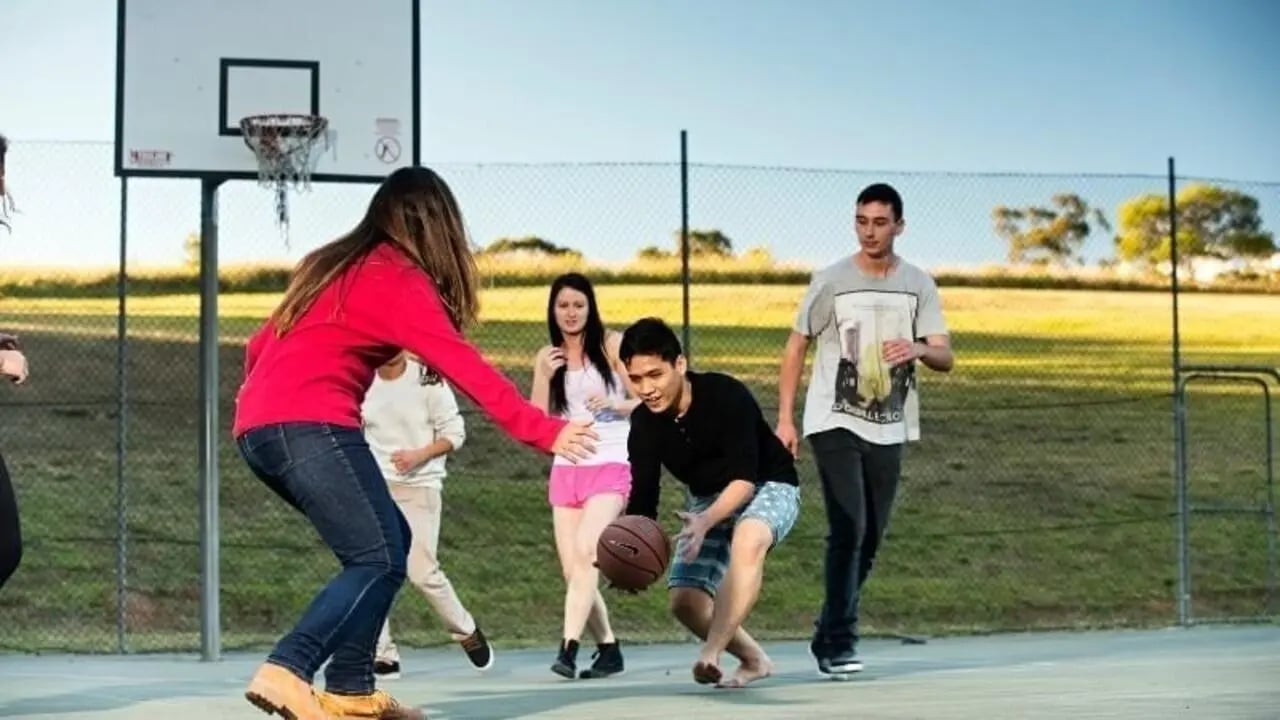 Students playing basketball on outdoor court playing area at Western Sydney University Campbelltown Village in Sydney Student Accommodation