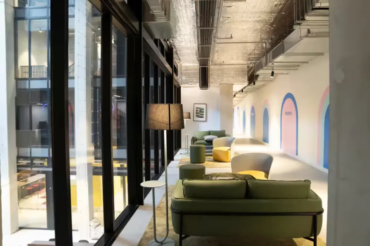 Green sofas armchairs floor lamp lounge area at Scape Cornell Place in Melbourne Student Accommodation