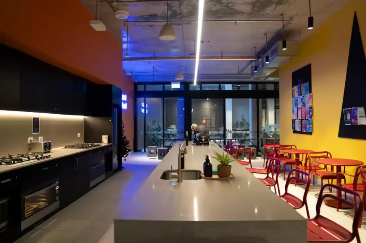 Modern kitchen with island counters and red seating area Kitchen at Scape Cornell Place in Melbourne Student Accommodation