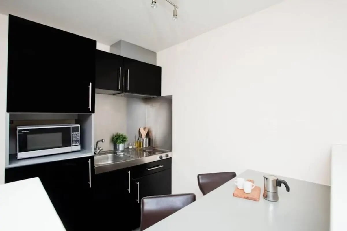 Microwave sink stove with chairs kitchen at Studio 58 in Bristol Student Accommodation