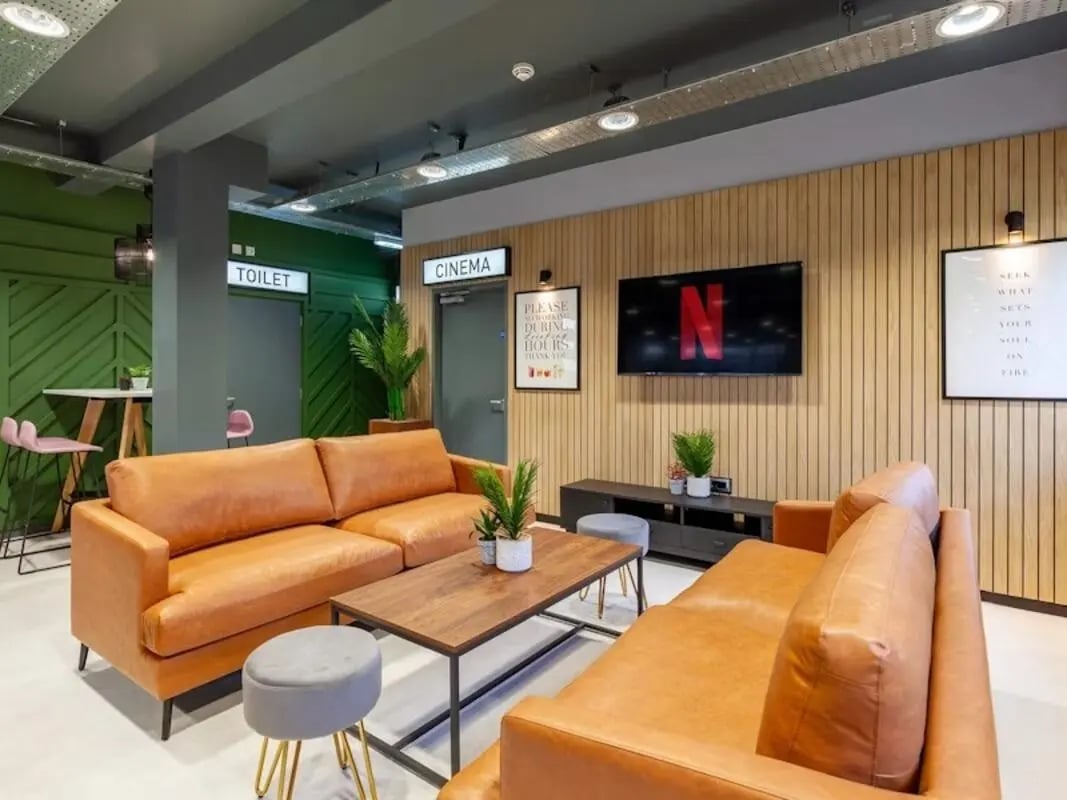 Two orange sofas coffee table Netflix screen living room at Filbert Village in Leicester Student Accommodation