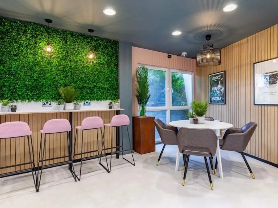 Green wall pink stools round table study area at Filbert Village in Leicester Student Accommodation