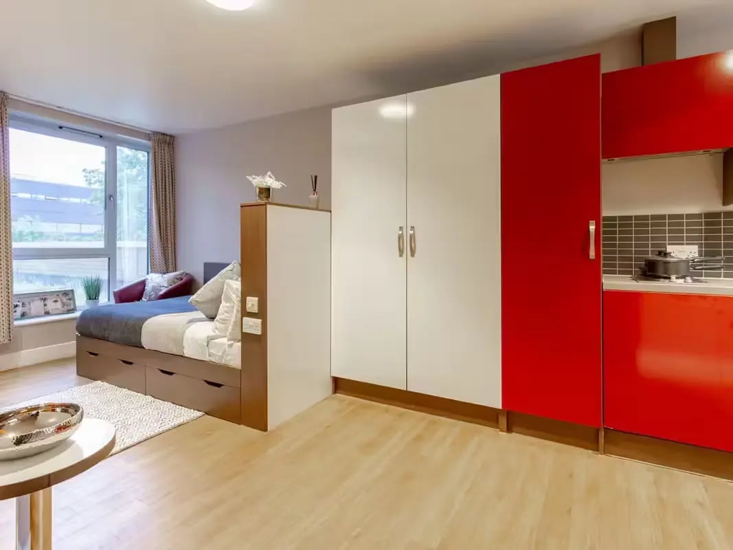 Bed with storage wardrobe kitchen area bedroom at Camden Hawley Crescent in London Student Accommodation