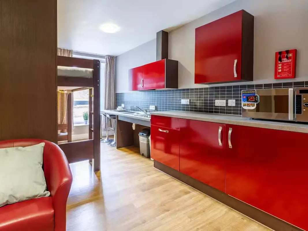 Bunk bed red sofa and red kitchen area kitchen at Camden Hawley Crescent in London Student Accommodation