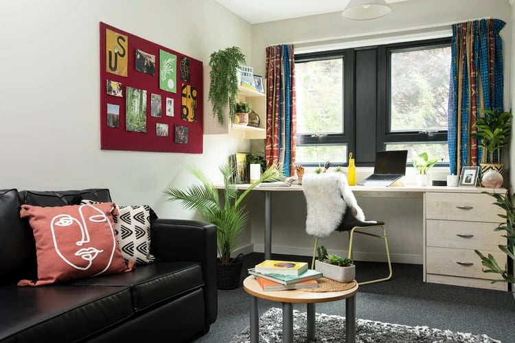 Sofa desk chair and bulletin board living room at Rahere Court in London Student Accommodation