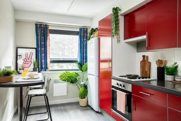 Red cabinets stove fridge with table and chairs Kitchen at Rahere Court in London Student Accommodation