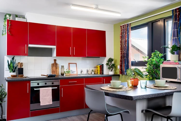 Red cabinets stove microwave and island kitchen at Rahere Court in London Student Accommodation