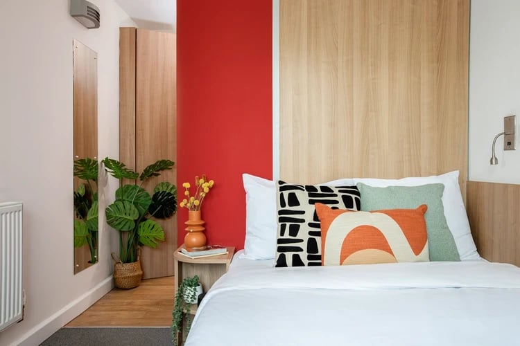 Bed pillows plant mirror doors bedroom at Wellington Lodge in London Student Accommodation