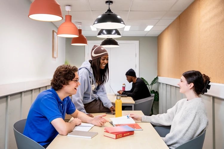 Students studying at tables with books and laptops common area at Wellington Lodge in London Student Accommodation