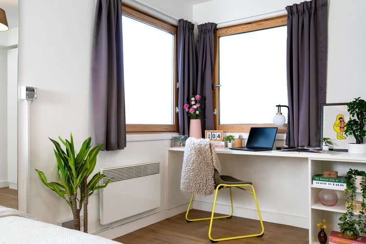 Desk with laptop, plants, and chair Study area at Piccadilly Court in London Student Accommodation