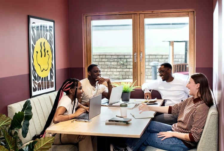 Students working on laptops at a communal table at Piccadilly Court in London Student Accommodation