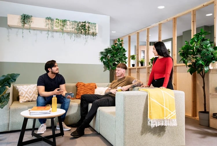 Students relaxing on sofa with plants living room at Piccadilly Court in London Student Accommodation
