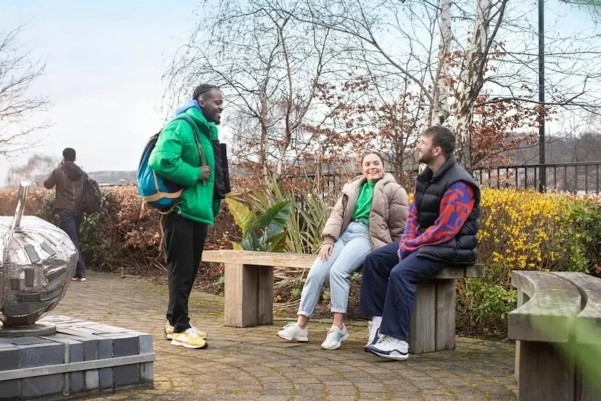 Students talking on bench outside building exterior at The Anvil in Sheffield Student Accommodation