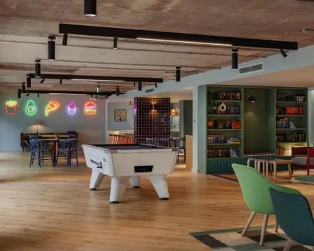 Pool table neon signs books shelves lounge area at Scape Shoreditch in London Student Accommodation