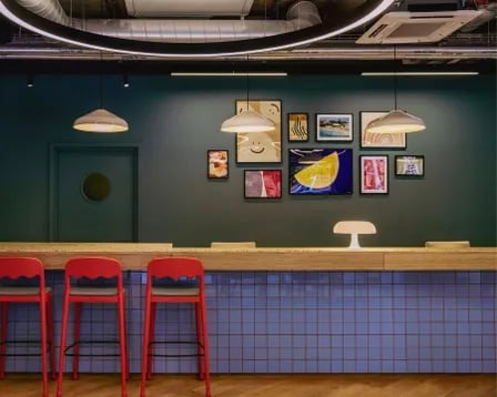 Red stools at counter with art living area at Scape Shoreditch in London Student Accommodation